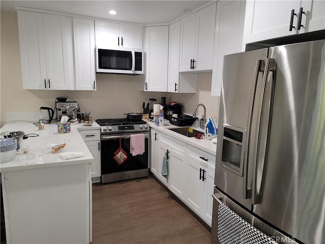 kitchen with white cabinets, appliances with stainless steel finishes, dark hardwood / wood-style floors, and sink