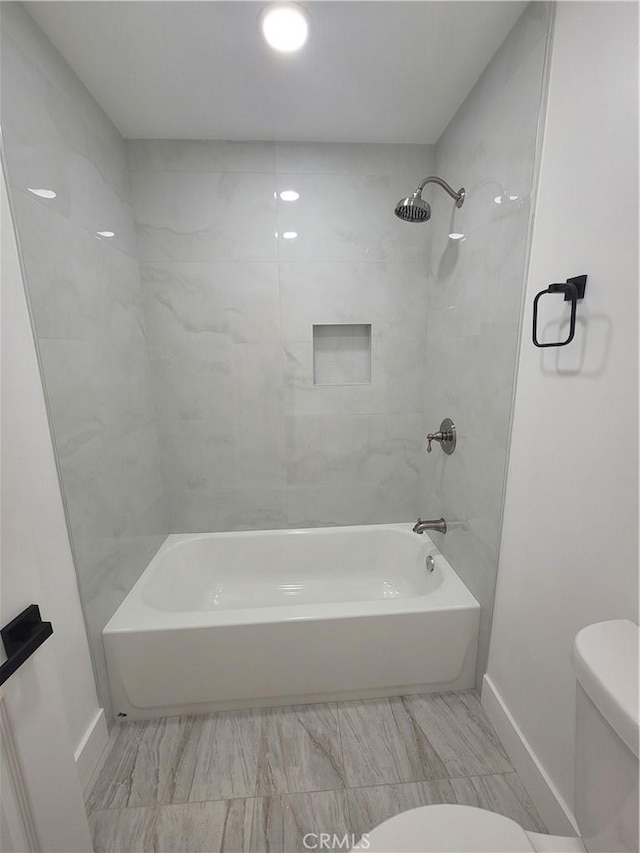 bathroom featuring tiled shower / bath and toilet