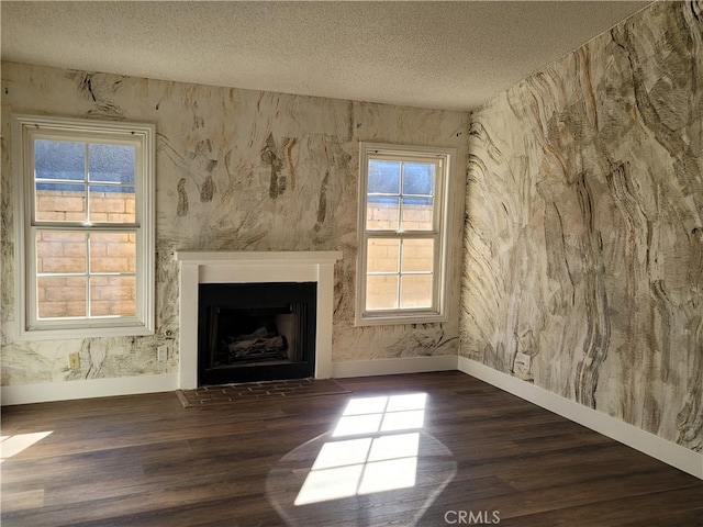 unfurnished living room featuring a textured ceiling, a wealth of natural light, and dark wood-type flooring