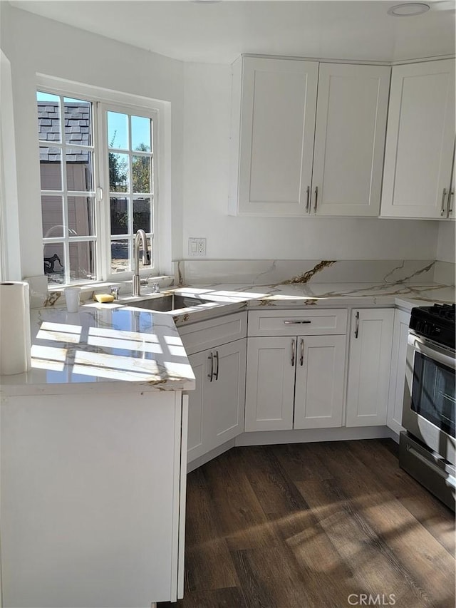 kitchen featuring stainless steel range, white cabinets, dark wood-type flooring, and sink