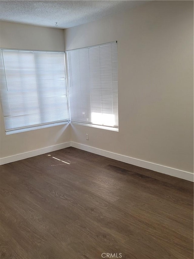 empty room with dark hardwood / wood-style flooring and a textured ceiling