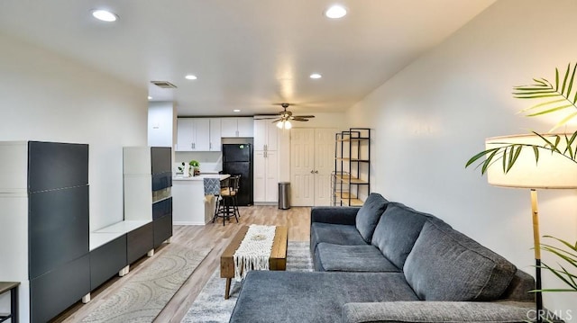 living room featuring light hardwood / wood-style flooring and ceiling fan