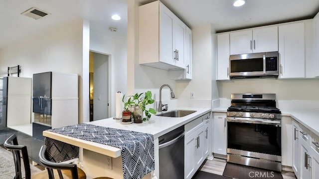 kitchen featuring sink, white cabinets, light wood-type flooring, and appliances with stainless steel finishes