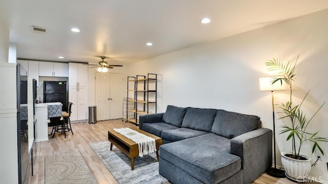 living room with light wood-type flooring and ceiling fan