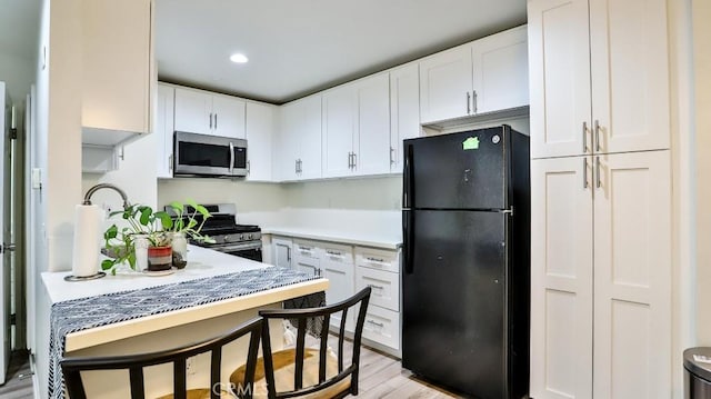 kitchen featuring white cabinetry, appliances with stainless steel finishes, and light hardwood / wood-style flooring