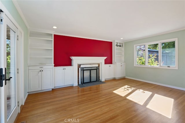 unfurnished living room featuring built in shelves, light hardwood / wood-style floors, and ornamental molding