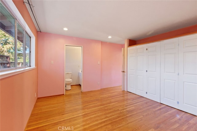 unfurnished bedroom featuring light wood-type flooring and connected bathroom