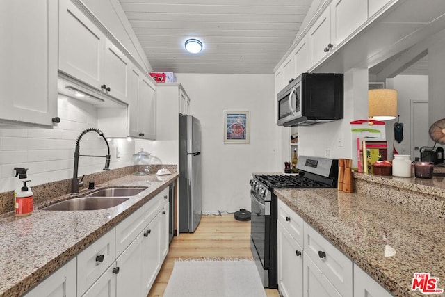 kitchen featuring white cabinetry, light stone counters, light hardwood / wood-style floors, decorative backsplash, and appliances with stainless steel finishes