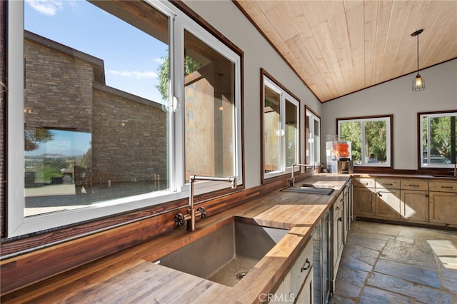 kitchen featuring butcher block counters, lofted ceiling, sink, decorative light fixtures, and wood ceiling