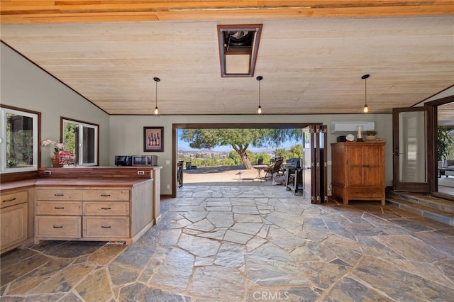 interior space featuring light brown cabinets, decorative light fixtures, vaulted ceiling, and a healthy amount of sunlight