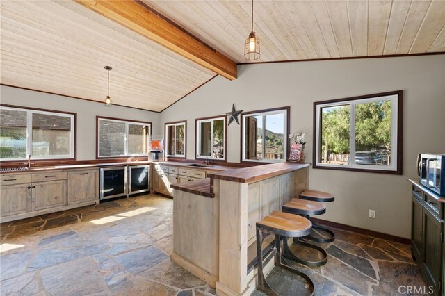 kitchen featuring pendant lighting, a breakfast bar, wine cooler, butcher block counters, and wood ceiling