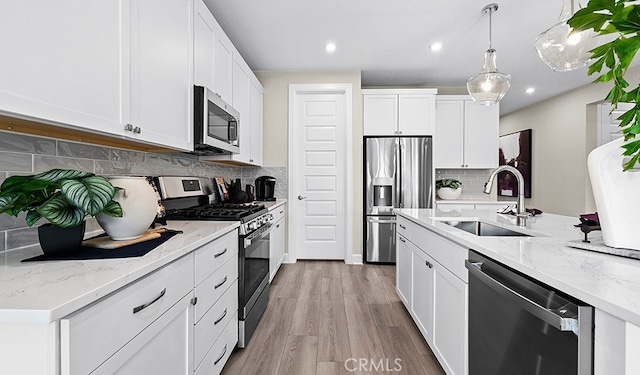 kitchen featuring sink, light hardwood / wood-style flooring, tasteful backsplash, white cabinetry, and stainless steel appliances