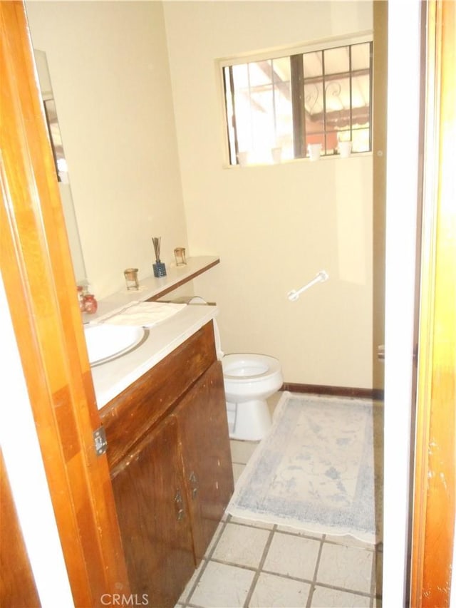 bathroom with toilet, vanity, and tile patterned floors