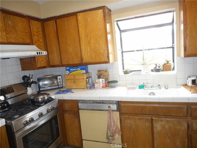 kitchen with gas stove, tile countertops, tasteful backsplash, and white dishwasher