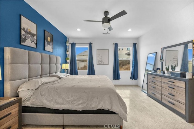 bedroom featuring ceiling fan, light colored carpet, and multiple windows