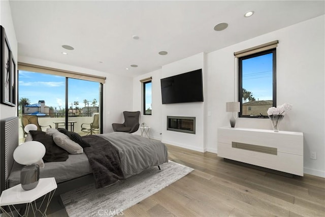 bedroom with access to outside, multiple windows, and hardwood / wood-style flooring