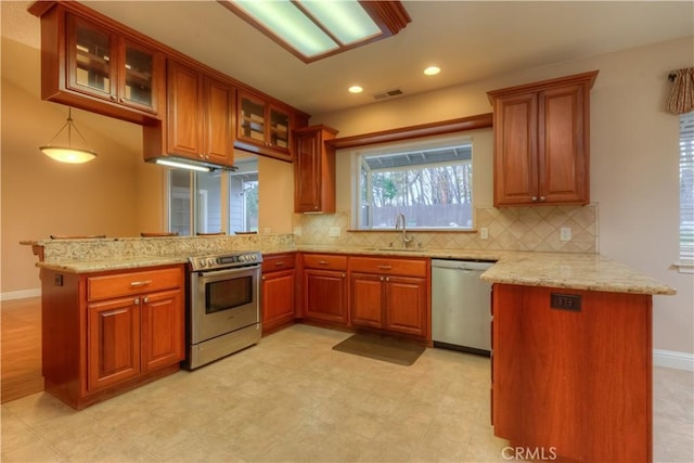 kitchen featuring kitchen peninsula, light stone counters, sink, and appliances with stainless steel finishes