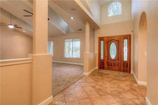 carpeted foyer with ceiling fan, high vaulted ceiling, and beam ceiling