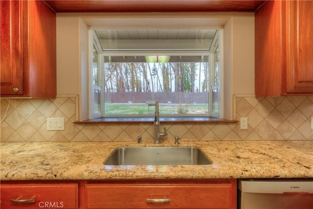 kitchen featuring sink, backsplash, dishwasher, and light stone counters