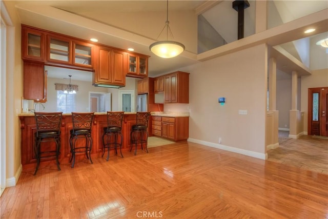 kitchen featuring a kitchen bar, light hardwood / wood-style floors, hanging light fixtures, high vaulted ceiling, and an inviting chandelier