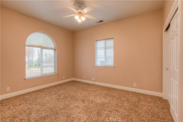 empty room featuring ceiling fan and carpet