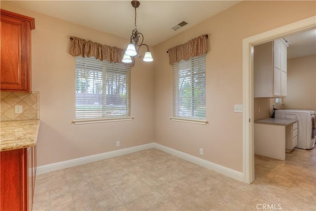 unfurnished dining area featuring washer / dryer and an inviting chandelier