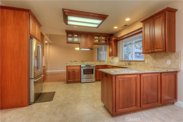 kitchen with tasteful backsplash, sink, kitchen peninsula, stainless steel appliances, and light stone counters