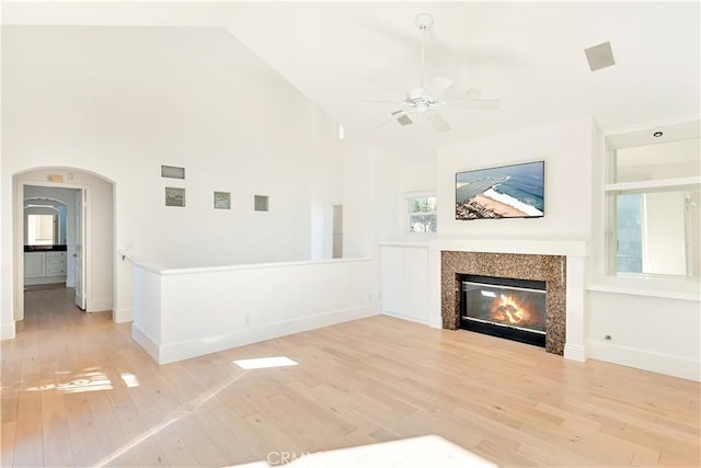 unfurnished living room featuring a tile fireplace, ceiling fan, light hardwood / wood-style flooring, and high vaulted ceiling