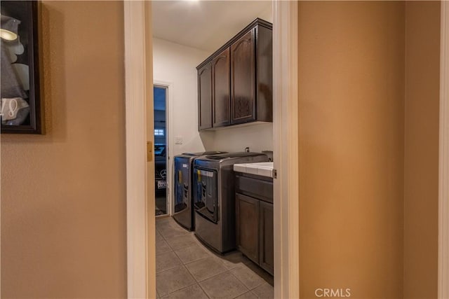 washroom with separate washer and dryer, light tile patterned floors, and cabinets