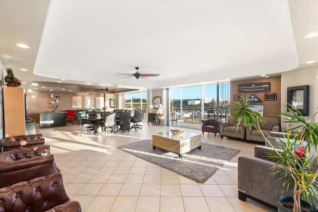 tiled living room with expansive windows, a wall unit AC, and ceiling fan