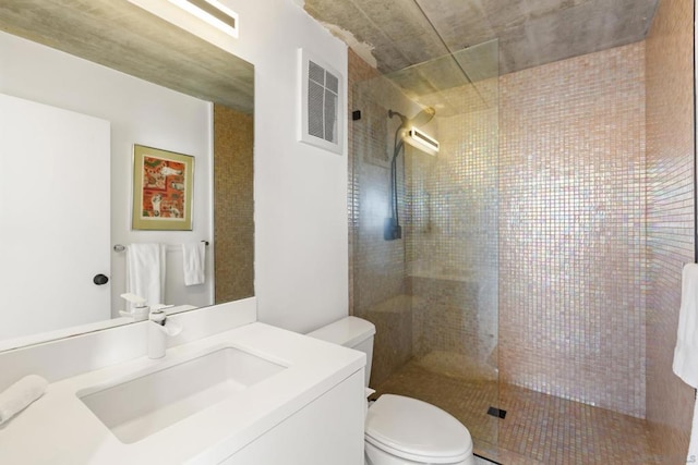 bathroom featuring a tile shower, vanity, and toilet