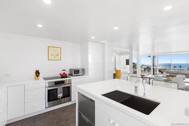 kitchen featuring black electric stovetop, white cabinetry, oven, and a water view