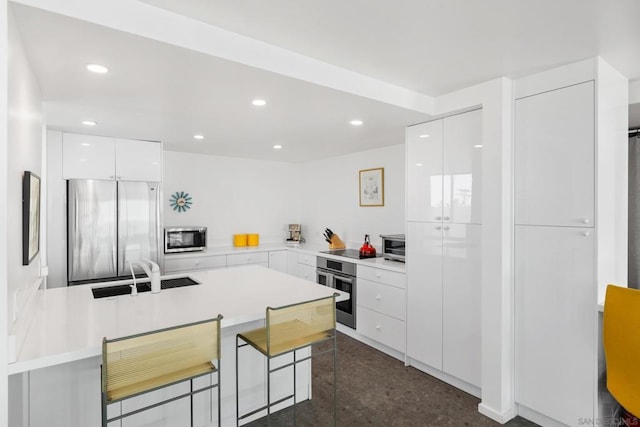 kitchen featuring white cabinets, stainless steel appliances, a breakfast bar area, and sink