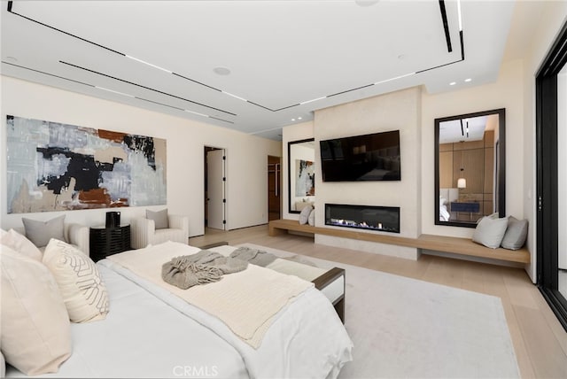 bedroom featuring a large fireplace and light hardwood / wood-style flooring