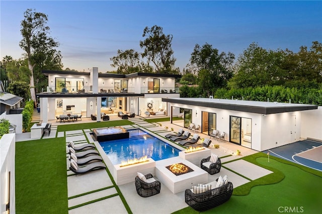 back house at dusk with a patio and an outdoor living space with a fire pit