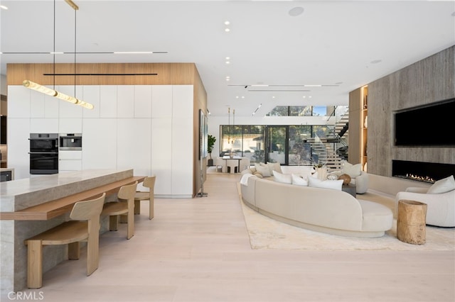 living room featuring light wood-type flooring, a large fireplace, and floor to ceiling windows