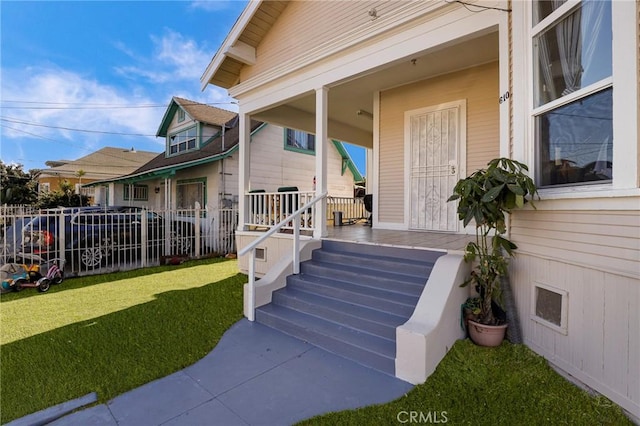 property entrance featuring a porch, a yard, and fence