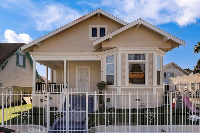 bungalow-style house with a fenced front yard and covered porch