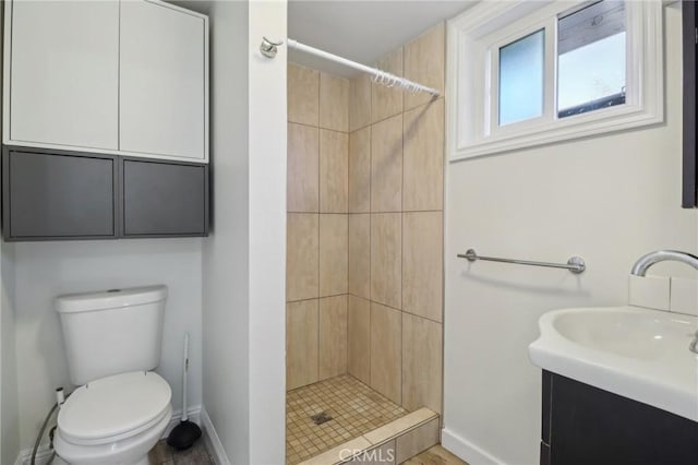 bathroom featuring vanity, toilet, and tiled shower