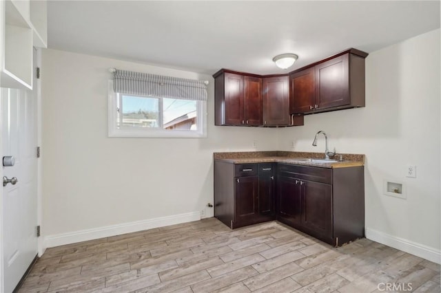 kitchen with dark brown cabinetry, sink, and light wood-type flooring