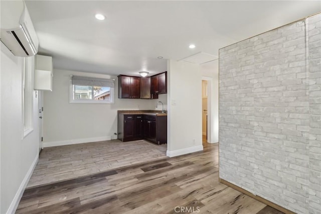 kitchen with light wood-type flooring, sink, and a wall unit AC