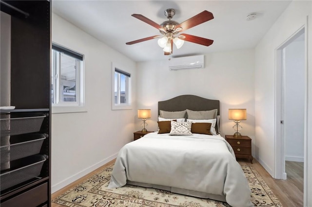 bedroom featuring light hardwood / wood-style flooring, a wall unit AC, and ceiling fan