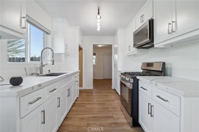 kitchen with light stone counters, white cabinetry, stainless steel appliances, and light hardwood / wood-style flooring