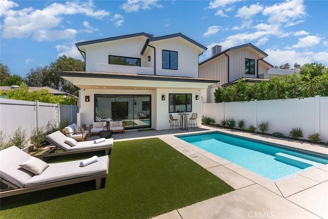 back of house with a fenced in pool, outdoor lounge area, a yard, and a patio