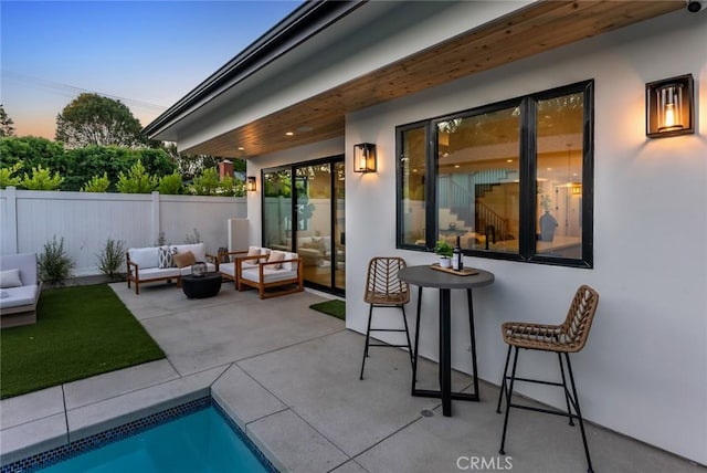 patio terrace at dusk featuring a fenced in pool and outdoor lounge area