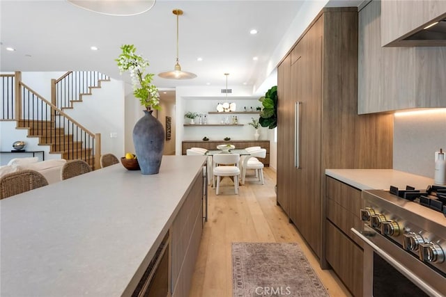 kitchen with pendant lighting, light wood-type flooring, and high end stainless steel range oven