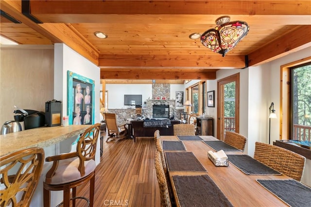 dining area with beam ceiling, a fireplace, wood ceiling, and hardwood / wood-style flooring