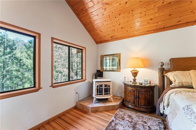 bedroom featuring wooden ceiling, light hardwood / wood-style floors, a wood stove, and vaulted ceiling