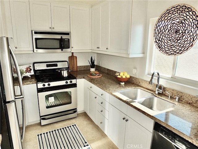 kitchen with light stone countertops, white cabinetry, sink, and appliances with stainless steel finishes