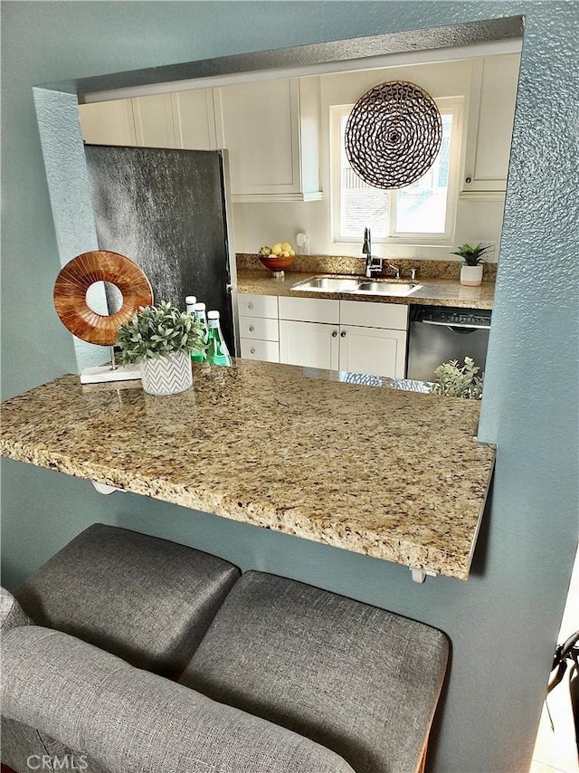 kitchen with dishwasher, white cabinets, sink, fridge, and light stone counters